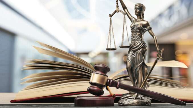 Lady justice stands over a gavel and law books