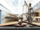 Lady justice stands over a gavel and law books